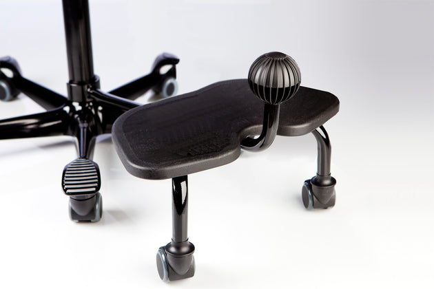 A black HÅG StepUp footrest attached to an office chair, designed to provide additional foot movement while sitting.