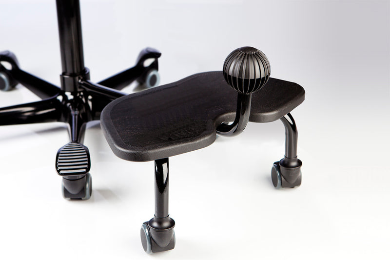 A black HÅG StepUp footrest attached to an office chair, designed to provide additional foot movement while sitting.