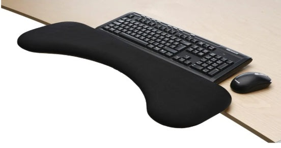 A black forearm support pad attached to a desk next to a keyboard and mouse, designed to provide comfort during computer use.