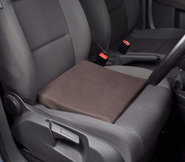 A black slimline wedge cushion placed on a car seat to demonstrate its use for posture support.