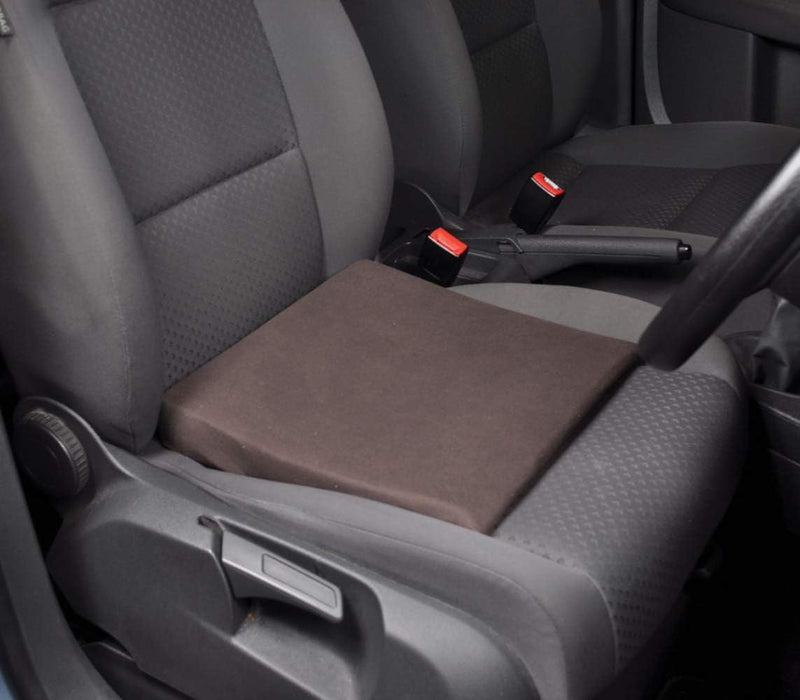 A black slimline wedge cushion placed on a car seat to demonstrate its use for posture support.