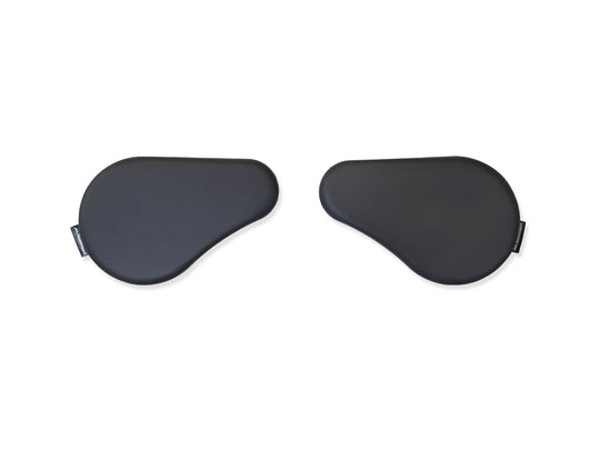 A pair of black faux leather arm supports designed for desk use, to alleviate neck, shoulder, and back strain.