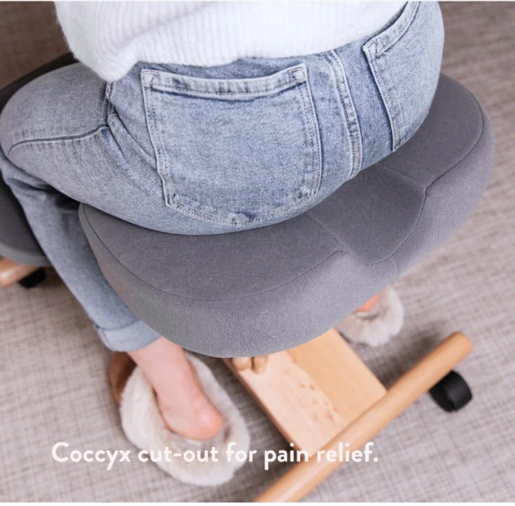 Person using a grey cushion with a coccyx cut-out on a chair.