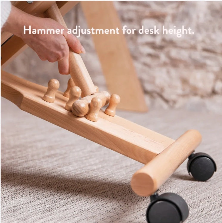 Wooden adjustable desk with hand using a hammer for height adjustment.
