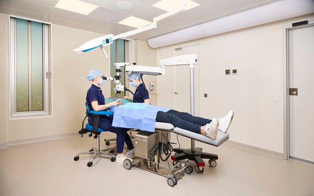 Medical setting with a patient on an examination table and two medical professionals.