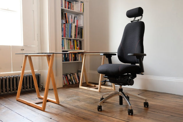 Black office chair in a room with a wooden table and bookshelf.